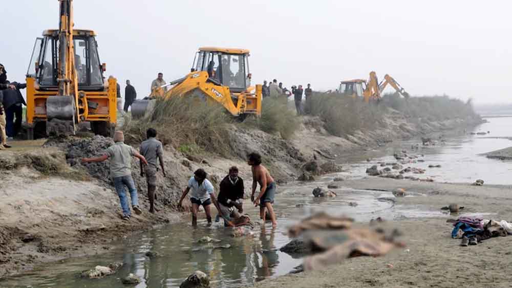  গঙ্গার তীরে চাপা দেওয়া দেহগুলিও বৃষ্টির কারণে কাদামাটি ধুয়ে গিয়ে বেরিয়ে পড়েছিল। 