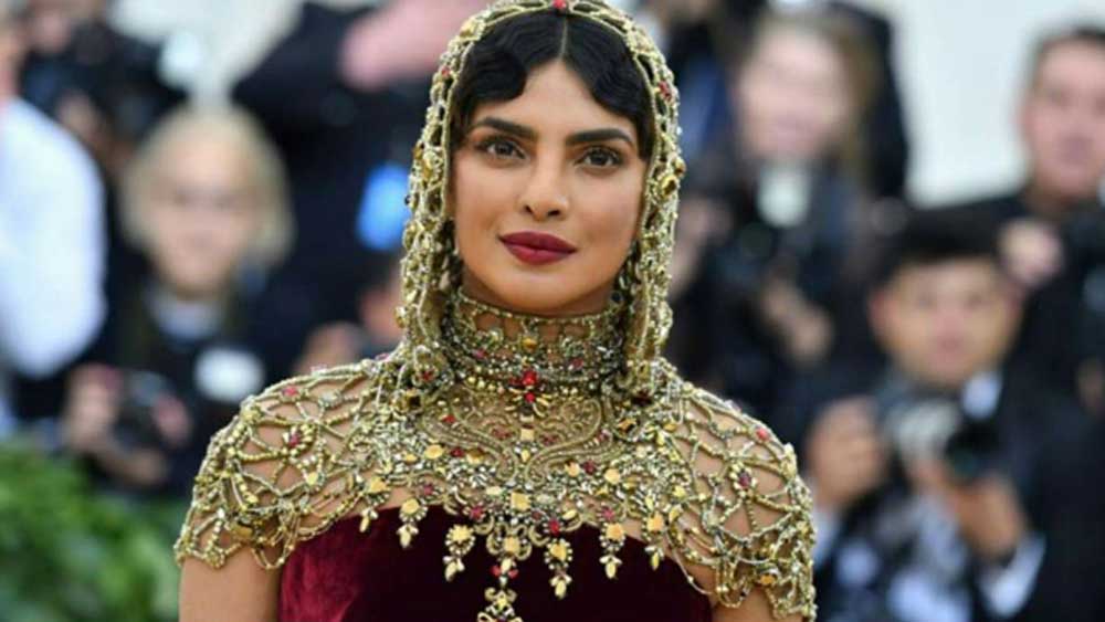 প্রিয়ঙ্কার এই পোশাকের এই দামের কারণ ছিল টুপির মতো তার উপরের অংশ। সোনালী রঙের এই অংশটি সোনা এবং মূল্যবান পাথর দিয়ে হাতে বোনা হয়েছিল। যে কারণে পোশাকের এত দাম।