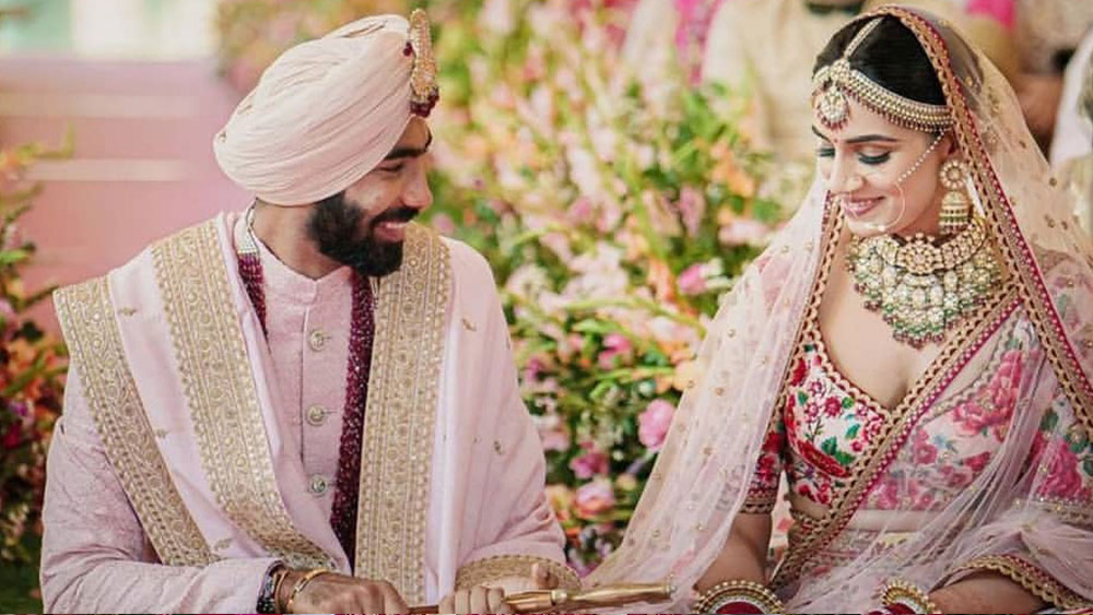 বিয়ের অনুষ্ঠান ছিমছাম হলেও বুমরা-সঞ্জনার পোশাক বেশ জমকালো ছিল। দু’জনের পোশাকেও ছিল একই রঙের ছোঁয়া। হালকা গোলাপি আভায় ঢাকা লেহঙ্গা-চোলির মাঝে সবুজ-গাঢ় জরির কাজে ঢাকা ছিলেন সঞ্জনা। 