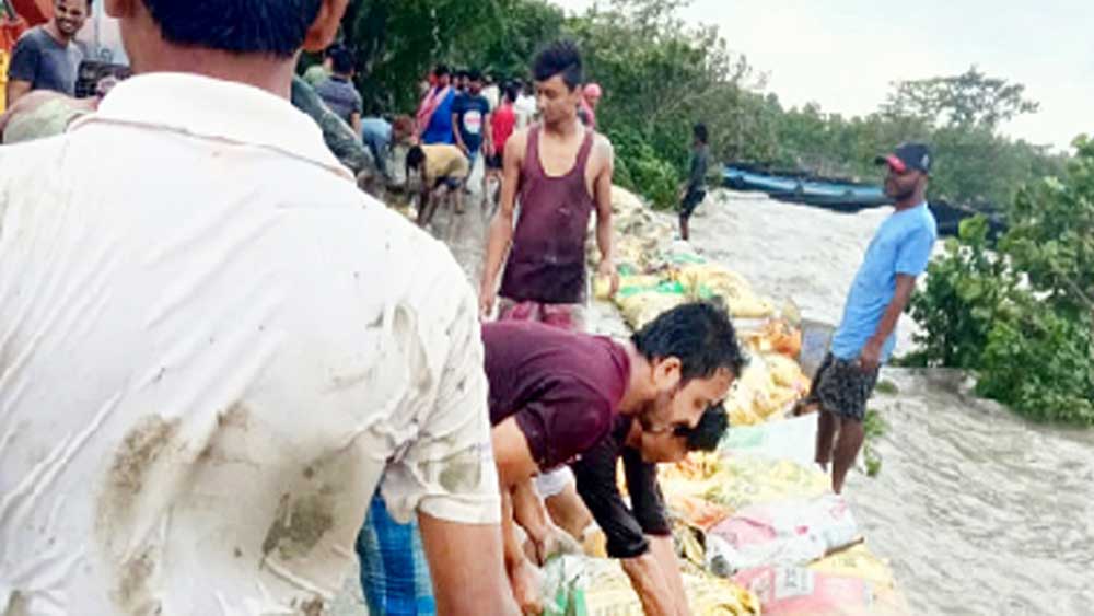 উলুবেড়িয়ার জগদীশপুরে নদীর জল যাতে গ্রামে না ঢুকতে পারে তার জন্য গ্রামবাসীরা বস্তাতে মাটি ভরে বাঁধ উঁচু করছেন। 