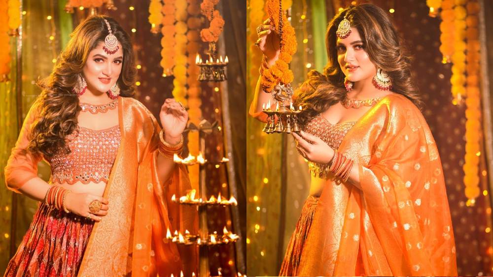 কানে, হাতে, মাথায় ভারী গয়না। স্মিত হাসি মুখে। কমলা রঙা লেহঙ্গা-চোলি ও গাঁদা ফুলের সাজে যেন কমলা সুন্দরী নায়িকা শ্রাবন্তী চট্টোপাধ্যায়।