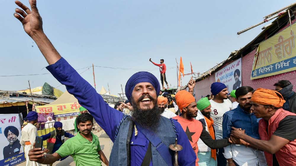 পিছনে বাঁশের গায়ে কাপড় জড়ানো বিক্ষোভ মঞ্চ। এক দিক খোলা। গত দেড় বছর ধরে কনকনে ঠান্ডায় কাঁপতে কাঁপতে এখানে নিয়ম করে বসেছেন, দুপুরে বাড়ি থেকে বেঁধে আনা ডাল-রুটি- ছাতু খেয়ে কেউ বা না খেয়ে ধুঁকতে ধুঁকতে জিইয়ে রেখেছেন আন্দোলন। 