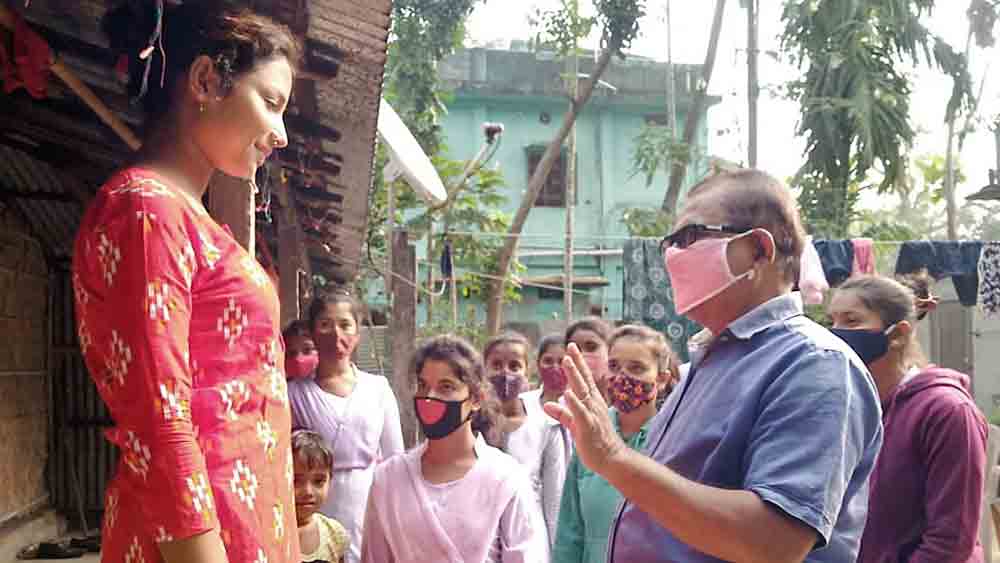 কথা: স্কুলে আসার কথা বলতে সহপাঠীদের সঙ্গে ছাত্রীর বাড়িতে গিয়ে বোঝাচ্ছেন শিক্ষক দিব্যেন্দু বিশ্বাস। মঙ্গলবার চাকুলিয়ায়। 