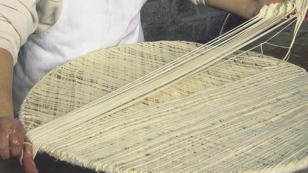 তারপর সেই সুতো আড়াআড়ি জড়ানো হয় কাঠের পাটাতনে। 