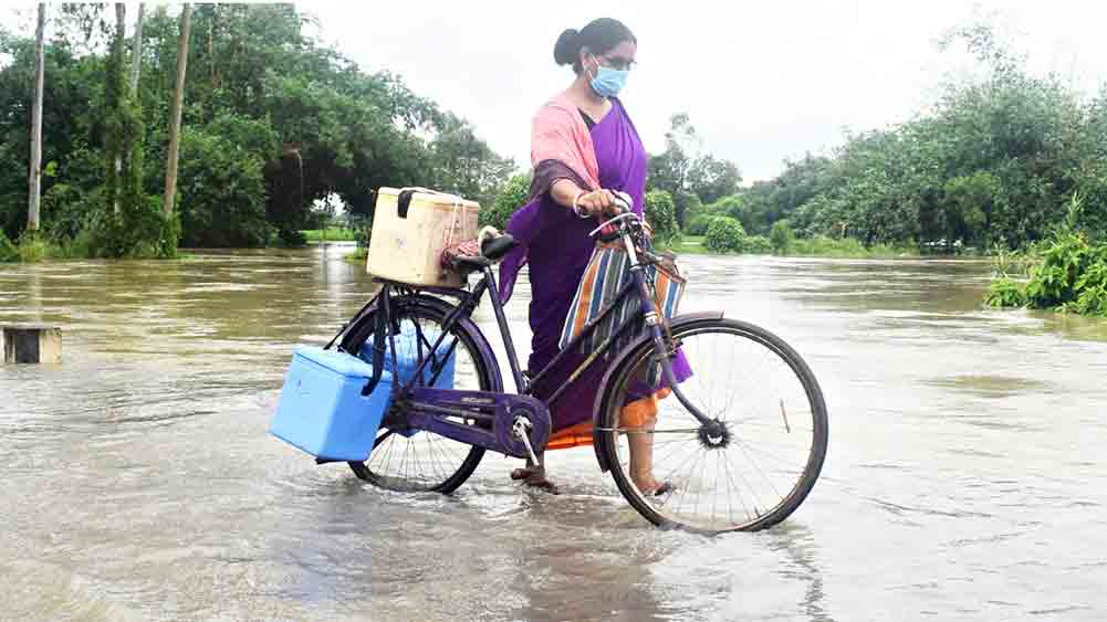 শিশুর স্বাস্থ্যের কথা ভেবে জল পেরিয়ে বাড়ি বাড়ি ঘুরছেন আশাকর্মীরা। 