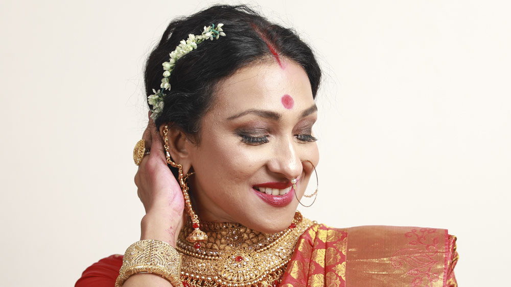 বাঙালিয়ানার কথা বলছিলেন। নিমেষে সেই ছোঁয়াই উঠে এল সাজেও। কপালে বড় লাল টিপ, সিঁথি ভরা সিঁদুর আর টকটকে লাল বেনারসি। যত্ন করে গলায় পরে নিলেন জমকালো হার, হাতে মানতাসা। একেবারে খাঁটি বঙ্গনারী। এবার পুজোয় এ সাজেই যে নিজেকে দেখতে চান ঋতুপর্ণা।