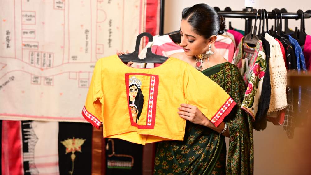 শাড়ির সঙ্গে মানানসই ব্লাউজ না হলে চলবে কী করে? তাই একই জায়গা থেকে বেছে নিলেন একটু দুর্গার মুখ কারুকাজ করা ব্লাউজও।