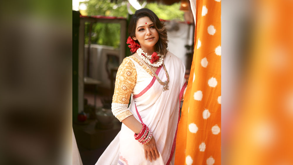লাল পাড় সাদা শাড়ি ছাড়া বাঙালির যে কোনও উৎসবই যে অসম্পূর্ণ! সুদীপ্তার জন্যও তাই সেই শাড়িই বেছে নিয়েছেন অনুশ্রী। আঁচলে সযত্নে আঁকা মা দুর্গার মুখ। অনুশ্রী বললেন, “দুর্গাপুজোয় মা দুর্গাকে প্রাধান্য দিতেই তৈরি হয়েছে এই শাড়ি।”