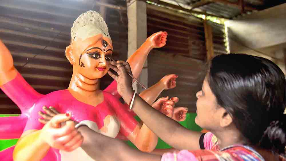 রূপ: দুর্গা প্রতিমার চোখ আঁকতে মহিলা শিল্পী। বালুরঘাটের খিদিরপুর পাল পাড়ায়। ছবি: অমিত মোহান্ত