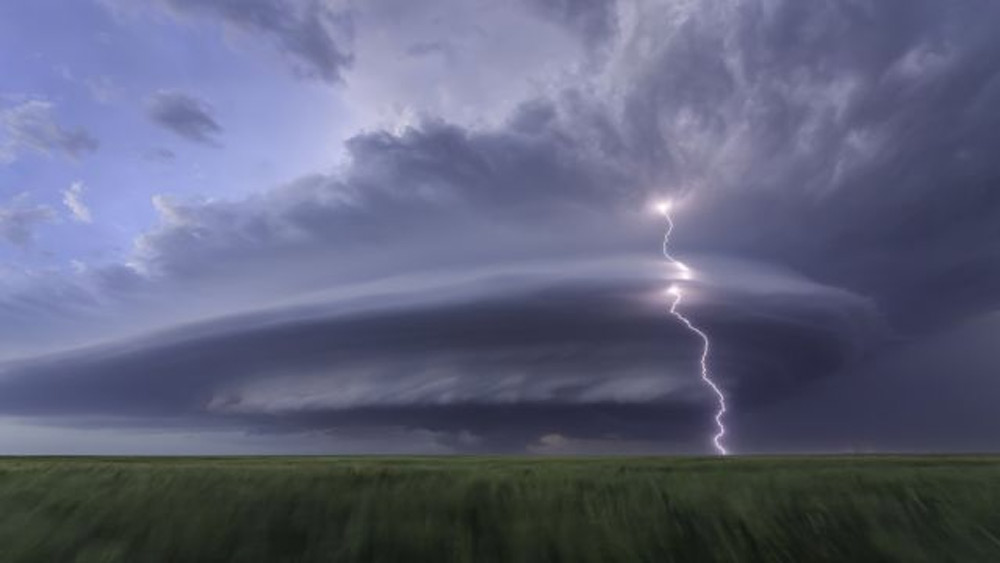 আকাশ ভেদ করে যেন কোনও ভিন্‌গ্রহী যান নেমে আসছে। প্রকৃতপক্ষে এটি ছিল ঘূর্ণিঝড়। আমেরিকার কানসাসের উপর তখন জট পাকাচ্ছিল সে। এই বিপর্যয়ের মুখে দাঁড়িয়ে ছবি নেওয়া দুঃসাধ্য কাজ। চিত্রগ্রাহক সেটাই সম্ভব করে তুলেছেন। ছবি সৌজন্য: লরা হেডিয়েন, সিয়েনা ইন্টারন্যাশনাল ফটো অ্যাওয়ার্ড ২০২১।