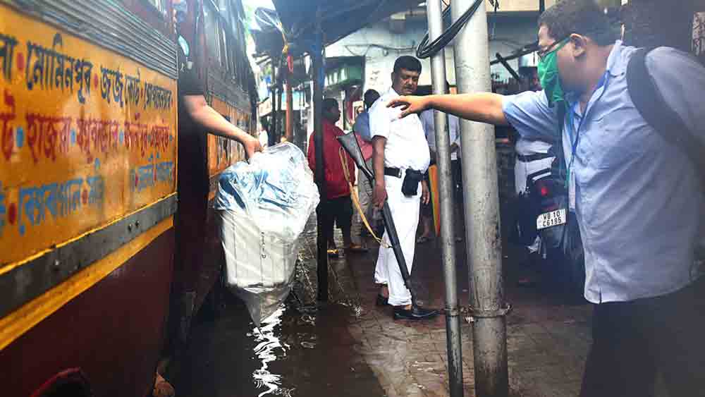  একবালপুরে একটি বুথে জল এড়িয়ে ইভিএম নামাচ্ছেন ভোটকর্মীরা। বুধবার। 