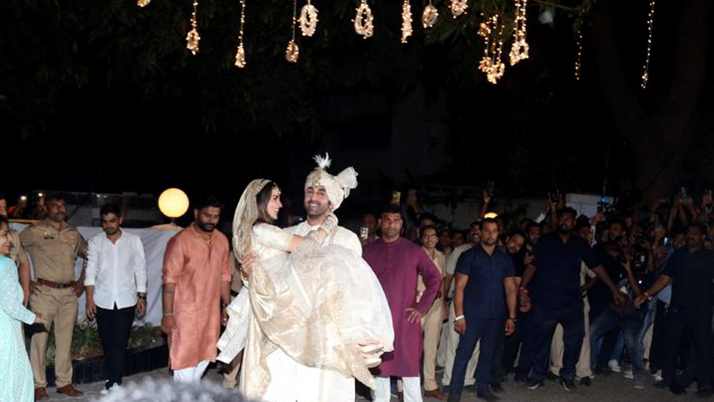 যুগল রূপ দেখে চোখ জুড়োতেই অনুরাগীদের বায়না, কোলে তুলতে হবে নতুন বউকে। পর্দায় কত বার নায়িকাকে কোলে নিয়েছেন ছোটা কপূর! এ তো জীবন-নায়িকা। মুখের কথা খসতে না খসতেই আলিয়া রণবীরের কোলে।