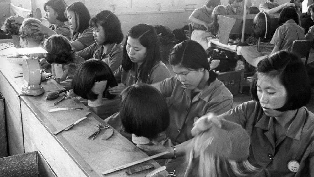 সন্তানের মাথায় এক ঢাল ঘন কালো চুল আসলে মা-বাবার থেকে পাওয়া মূল্যবান উপহার। চিরাচরিত ভাবে এমনই ধারণা দক্ষিণ কোরীয়দের। তবে ষাটের দশকে সেই উপহার বিক্রি করতে বাধ্য হয়েছিলেন সে দেশের বহু মহিলা। তা থেকে গড়ে উঠেছিল পরচুলা তৈরির কারখানা। সেই পরচুলা রফতানি করেই দেশের অর্থনৈতিক শক্তি বাড়িয়ে নিয়েছিলেন রাষ্ট্রশাসকেরা। তবে এই উজ্জ্বল অধ্যায়েও ছিল গাঢ় অন্ধকার।