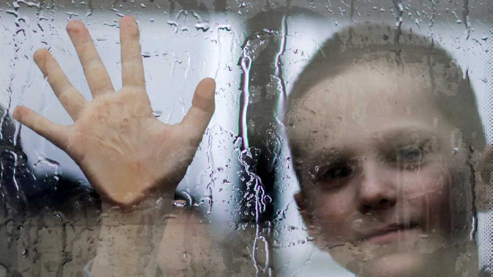  সরকারি নির্দেশ, দেশে থাকতে হবে পুরুষদের। পরিবারকে নিরাপদ স্থানে সরাতে হচ্ছে। মাঝখানে ব্যবধান কাচের জানালা। বিদায়বেলায় বাবা এবং শিশুসন্তানের আবেগঘন মুহূর্তের ছবি৷