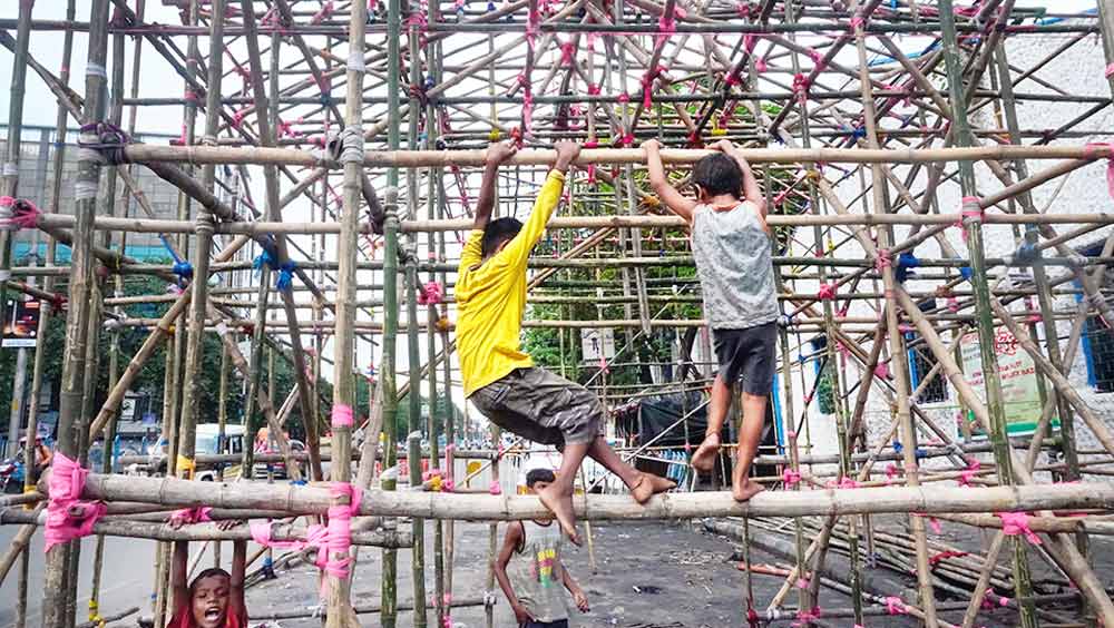 আহা কী আনন্দ..: নির্মীয়মাণ মণ্ডপ ঘিরে খেলায় মেতেছে খুদেরা। বুধবার, মল্লিকবাজারে।