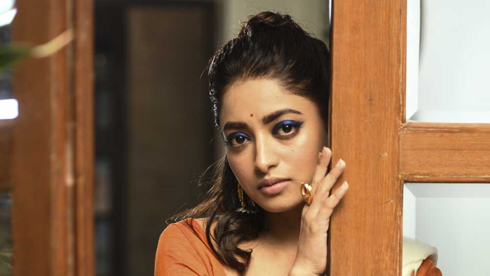 বাড়িতে তত ক্ষণে পুজোর তোড়জোড়। সুন্দরী ইশা সাজ সেরে দরজা খুলতেই মঙ্গল ঘটে কলা গাছের উঁকি। কন্যের কানে বড় ঝুমকো, আঙুল জোড়া আংটি। চোখে লাইনার, শ্যাডো। ঠোঁটে প্যাস্টেল শেডের লিপস্টিক। যা দেখে ঘোর লাগে চোখে!