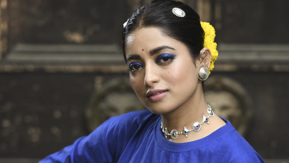 যুগের চাহিদা মেনে জিন্স, টপ পরেন। হলুদ গোলাপে সাজানো খোঁপায় বসন্ত পঞ্চমীর রেশ। মাথা থেকে আঙুলে রুপোর গয়না। সেই আঙুল ছুঁয়েছে তানপুরার তার।