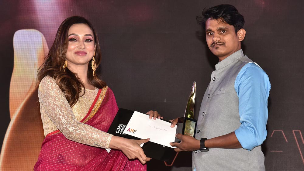 মিমি চক্রবর্তীর হাত থেকে ‘মেরিট অ্যাওয়ার্ড’ নিলেন সত্যরাজন দাস। 