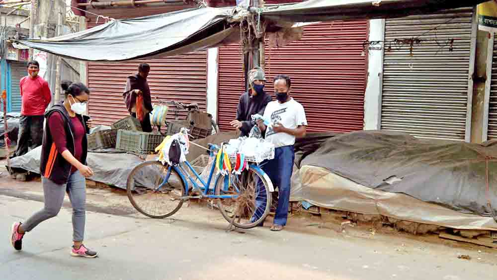 মুখে আবরণ: সংক্রমণে রাশ টানতে বন্ধ দোকানপাট। সেখানেই সাইকেল নিয়ে দাঁড়িয়ে চলছে মাস্ক বিক্রি। মঙ্গলবার, নাগেরবাজারে। 