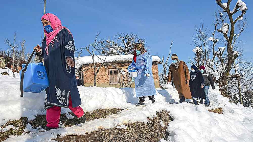 অবিচল :বরফ ঠেলেই করোনার প্রতিষেধক নিয়ে বাড়ি বাড়ি ঘুরছেন স্বাস্থ্যকর্মীরা। বুধবার মধ্য কাশ্মীরের বদগাম জেলার প্রত্যন্ত গ্রামে। পিটিআই