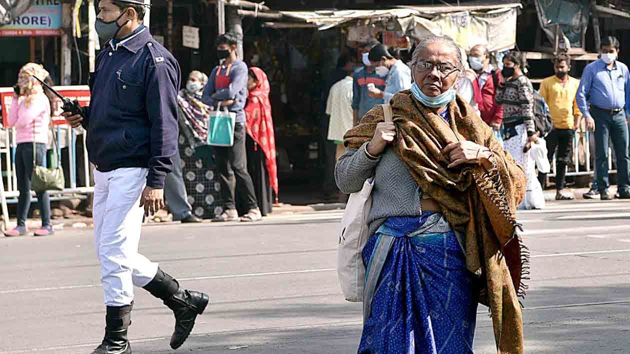 উত্তর কলকাতায় পুলিশের নজর এড়িয়ে মাস্ক নামিয়েই পথে এক প্রৌঢ়া।