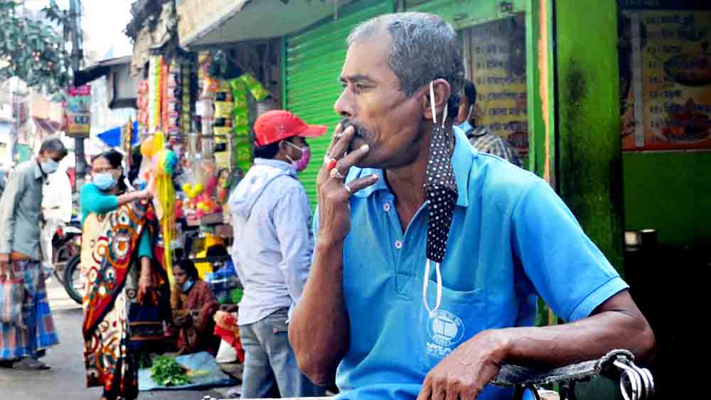 সুখটান: মাস্ক নামিয়ে চলছে ধূমপান। বৃহস্পতিবার বনগাঁয় ছবিটি তুলেছেন নির্মাল্য প্রামাণিক