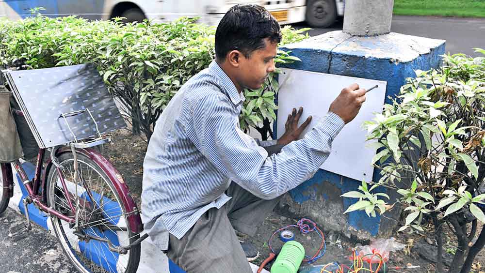 ডিভাইডারের উপরে বিপজ্জনক ভাবে খোলা থাকা বাতিস্তম্ভ ঢেকে দেওয়ার কাজ করছেন পূর্ত দফতরের এক কর্মী। রবিবার, ময়দানের কাছে।