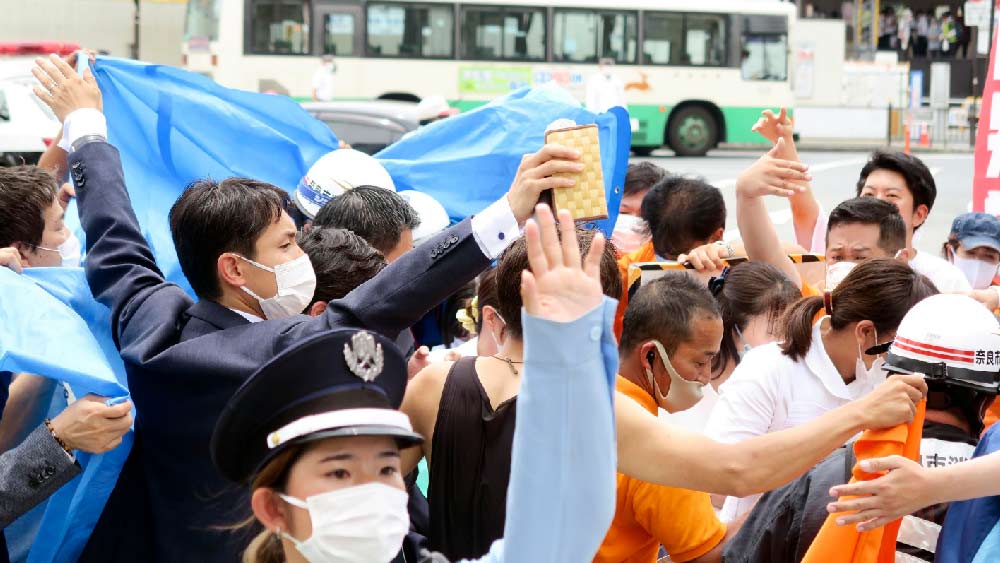 পশ্চিম জাপানের নারা শহরে একটি কর্মসূচিতে বক্তৃতা করছিলেন শিনজো আবে। তাঁকে চার পাশে ঘিরেছিলেন অনেকে।