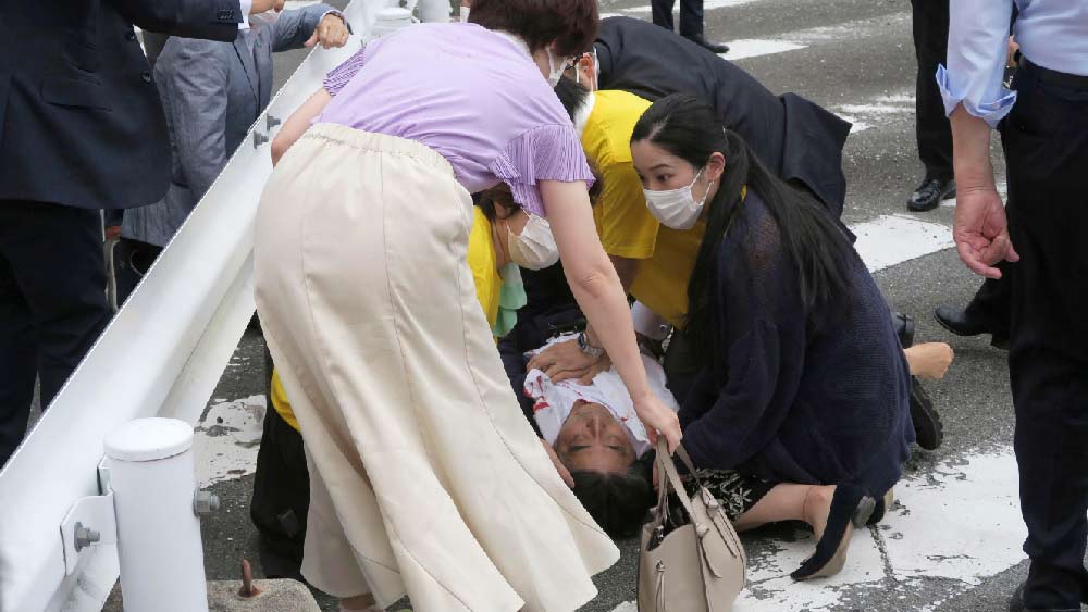 গুলিবিদ্ধ হয়ে রাস্তায় লুটিয়ে পড়লেন শিনজো। জামায় রক্তের দাগ। উদ্ধার করতে জড়ো হয়েছেন কয়েক জন। 