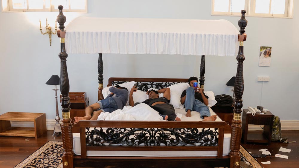 যেখানে দিন কয়েক আগে পর্যন্ত ঘুমোতেন রাজাপক্ষে, সেখানেই হাত-পা ছড়িয়ে ঘুমোচ্ছে কেউ। আবার কেউ গা এলিয়ে ব্যস্ত মোবাইলে। প্রেসিডেন্টের প্রাসাদ রাতারাতি যেন পর্যটনস্থল হয়ে উঠেছে। 