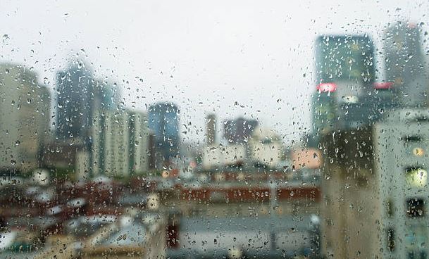 বৃষ্টির কাচ থেকে স্লো মোশনে গড়িয়ে পড়ছে বৃষ্টির ফোঁটা