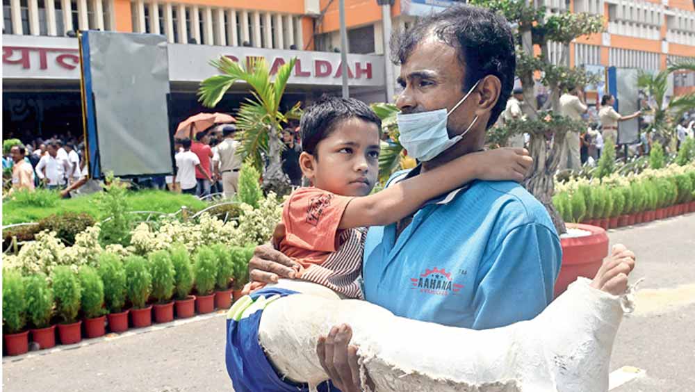 অসহায়: পা ভাঙা ছেলেকে কোলে নিয়েই ভোগান্তির শিকার সুব্রত কুণ্ডু। বৃহস্পতিবার, শিয়ালদহ স্টেশনে।