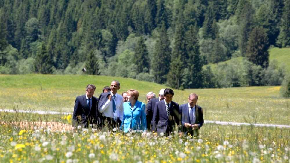 বরফে ঢাকা পাহাড়ের নীচে সবুজ ঘাসে এলোমেলো ভাবে দাঁড়িয়ে আছেন রাষ্ট্রনেতারা। এঁদের অনেকেই প্রথম বিশ্বের শক্তিশালী দেশের সর্বেসর্বা। সাধারণত ঠান্ডাঘরের চার দেওয়ালের মধ্যে ওঁদের দেখা যায়। তবে এখানে ওঁদের পদ বা ক্ষমতা বোঝার উপায় নেই। এ-ও বোঝার উপায় নেই যে কিছু ক্ষণ পরেই কে আন্তর্জাতিক রাজনীতি এবং কূটনীতির কোন গুরুতর কলকাঠিটি নাড়বেন। এখানেই জার্মানির হোটেল স্লস এলমাও-এর মহিমা।