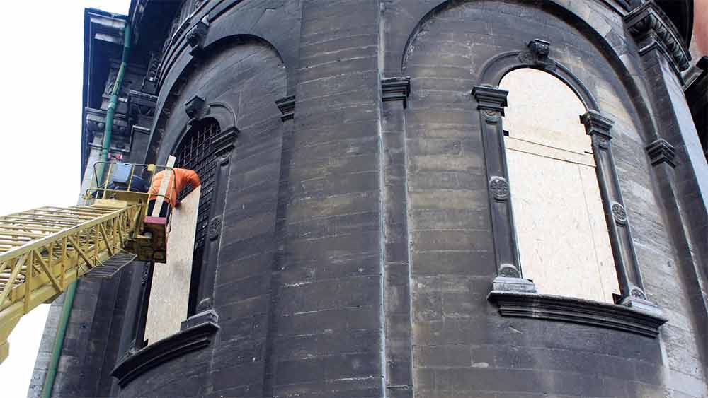 আগুন নেভানোর উঁচু সিঁড়িতে চড়েছেন অনেকে। এর পর গির্জার জানলাগুলিতে একের পর এক অর্ধচন্দ্রাকৃতি ধাতব পাত এঁটে দিচ্ছেন তাঁরা। 