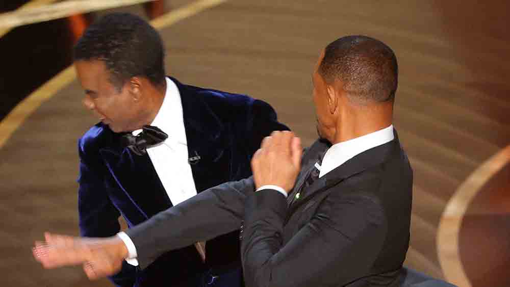 সোমবার অস্কারমঞ্চে স্ত্রী জেডা পিঙ্কেট স্মিথকে পরোক্ষে কটাক্ষ করেন এ বারের অস্কার পুরস্কার বিতরণী অনুষ্ঠানে সঞ্চালক তথা কমেডিয়ান ক্রিস রক। বলেছেন, ‘‘জি আই জেন-এর সিক্যুয়েলের অপেক্ষায় রয়েছি।’’ সে মন্তব্যে দৃশ্যতই অখুশি হয়েছেন জেডা। তার পরই সটান মঞ্চে উঠে উইলের চড় পড়েছে ক্রিসের গালে। ব্যাপারটা যে সাজানো নয়, তা বোঝা গিয়েছে উইলের পাল্টা মন্তব্যে। নিজের আসনে বসে ক্রিসের উদ্দেশে চিৎকার করে উঠেছেন উইল, ‘‘তোমার (নোংরা) কথা থেকে আমার স্ত্রীকে দূরে রাখো!’’