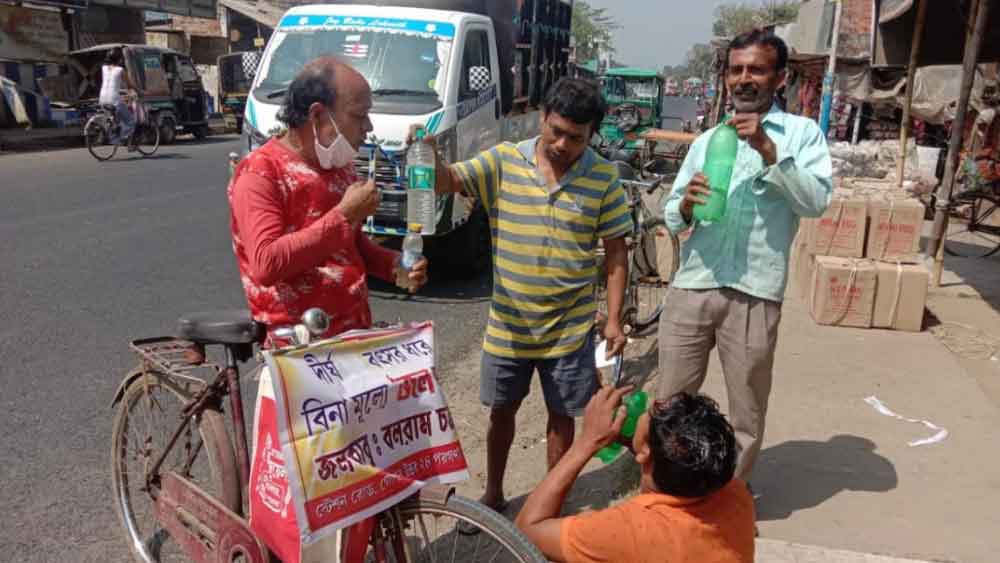 রাস্তায় সাধারণ মানুষকে জলপান করাতে ব্যস্ত বলরাম চক্রবর্তী।