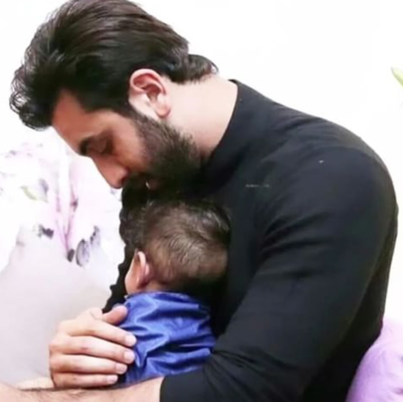 অন্য আর একটি ছবিতে দেখা গিয়েছে রণবীরকে। নীল জামা পরা ছোট্ট এক শিশুকে কোলে নিয়ে রণবীর বসে আছেন। পরম মমতায় আগলে রেখেছেন একরত্তিকে। শিশুর মুখ ক্যামেরার উল্টো দিকে ফেরানো। 