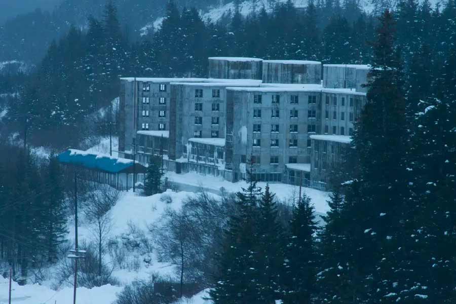 ছবির মতো দেখতে শহর। চারপাশে সবুজালি, উঁচু পাহাড়। সেই পাহাড়ের গায়ে, মাথায় পুরু বরফের পরত। আর তাদের উপত্যকায় জেগে রয়েছে একটি মাত্র বহুতল। ধবধবে সাদা ১৪ তলা ভবনের গায়ে বাদামি রঙের পোঁচ।