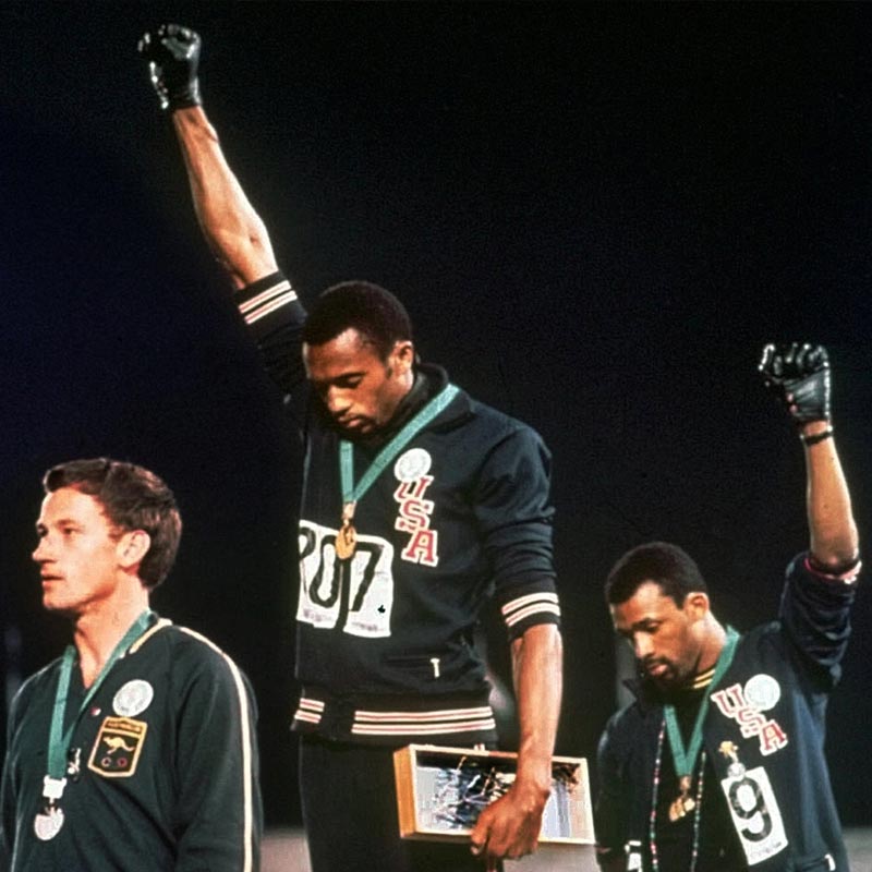 ১৯৬৮ সালের মেক্সিকো অলিম্পিক্সে আমেরিকার দুই কৃষ্ণাঙ্গ দৌড়বিদ টমি স্মিথ এবং জন কার্লোস যথাক্রমে সোনা এবং ব্রোঞ্জ পেয়েছিলেন। পোডিয়ামে দাঁড়িয়ে মাথা নিচু করে হাত তুলে দাঁড়িয়ে থাকতে দেখা যায় দু’জনকে।