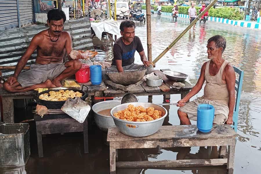 জলমগ্ন এলাকায়  ক্রেতার আশায় দোকানিরা।