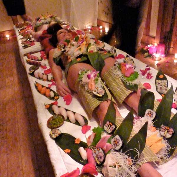 খাবার-সজ্জিত সেই নগ্ন মহিলার চারপাশে গোল হয়ে ঘিরে খেতে বসেন বাড়িতে আমন্ত্রিত অতিথি বা রেস্তোরাঁয় খেতে-আসা লোকজন।