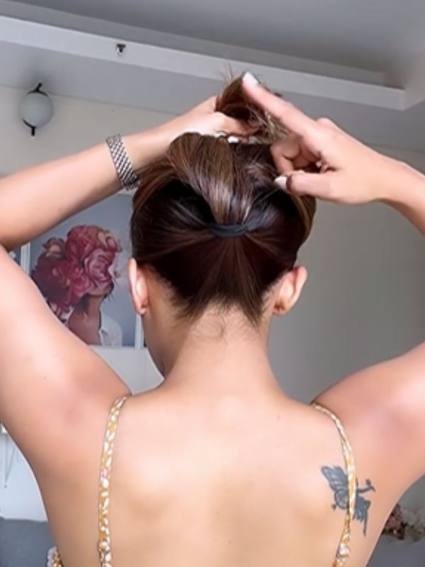 পুরো বাঁধা চুল তার পর সামনের দিকে উল্টে এনে প্রথম হেয়ার টাইয়ের দিকে আলতো করে টেনে আনুন। চুলের পুরো অংশ পাকিয়ে ভিতর দিকে ঢুকিয়ে দিন। 