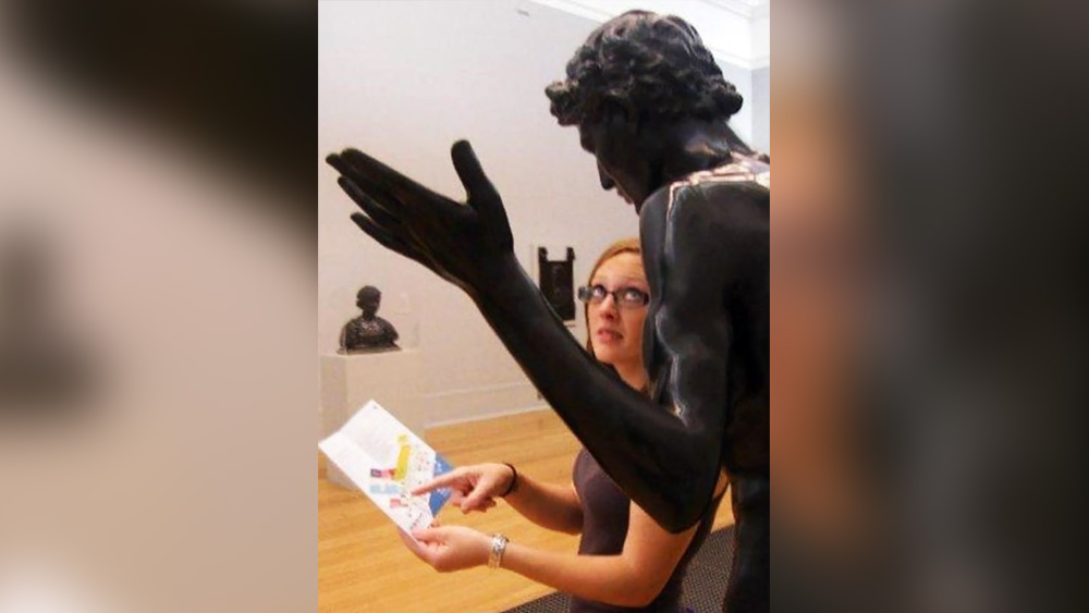 মিউজিয়াম ঘুরতে গিয়ে হারিয়ে গিয়েছেন? মানচিত্র দেখেও খুঁজে পাচ্ছেন না? তা হলে ভরসা একটাই। আশপাশে কেউ থাকলে তাঁর কাছে সাহায্য নিন। কেউ না কেউ সঠিক পথের হদিস দিয়ে দেবেন। এই ছবিতেও পাথরের মূর্তির সঙ্গে এরকমই পোজ দেওয়া হয়েছে। মহিলাটি মানচিত্রে জায়গাটি দেখাচ্ছেন এবং পাথরের মূর্তিটির হাত এমন দিকে রয়েছে যা দেখে মনে হচ্ছে তিনি সঠিক পথের নির্দেশ দিচ্ছেন।