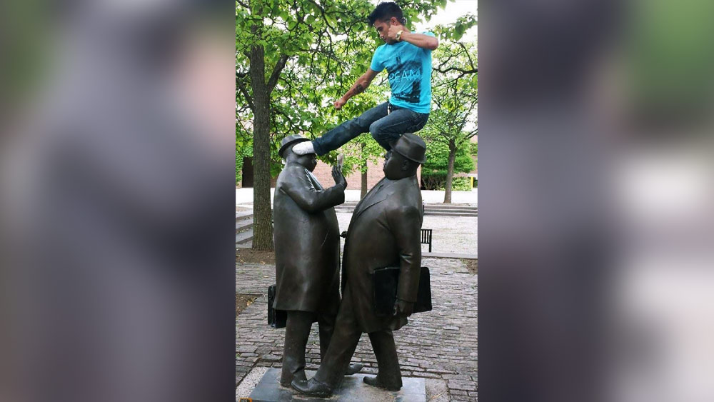 সকালে স্কুল-কলেজ-অফিস যাওয়ার তাড়া সকলেরই থাকে। রাস্তায় চলাচলের সময় প্রায়ই ধাক্কা লেগে যায় পথচারীদের সঙ্গে। কালো পাথরের মূর্তিগুলিও এই ধাঁচেই বানানো। কিন্তু নীল টি-শার্ট পরা ছেলেটি মূর্তি দু’টির উপর উঠে এমন ভাবে পোজ দিয়েছে, তাকে দেখে মনে হচ্ছে সে যেন এক ব্যক্তির ঘাড়ে উঠে দ্বিতীয় ব্যক্তিটির মুখে মারছে।