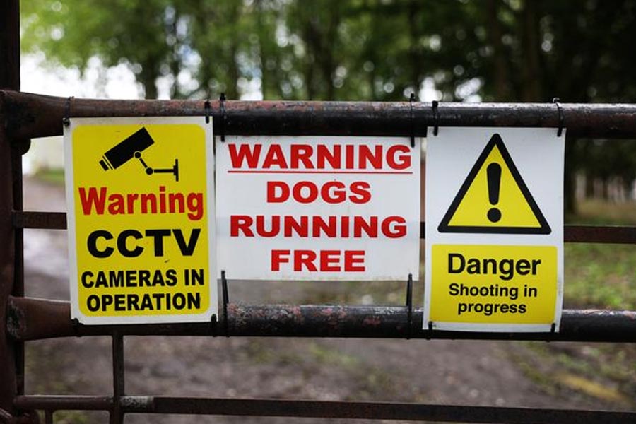 বেড়ার উপর সাদা বোর্ডে কালো অক্ষরে লেখাও রয়েছে ‘ভেতরে শ্যুটিং চলছে’, ‘কুকুর হইতে সাবধান’ ইত্যাদি।