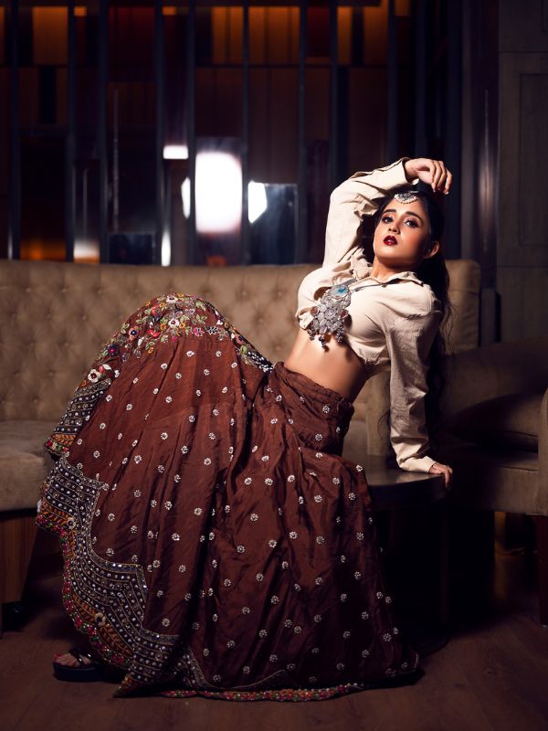 চওড়া এমব্রয়ডারি করা স্কার্টের সঙ্গে সাদা শার্ট বদলে দিয়েছে মিঠাইয়ের চেনা সাজ। 