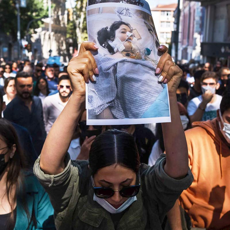 মাহশার মৃত্যুর প্রতিবাদে ইরানের রাস্তায় বিক্ষোভের আগুন জ্বলে উঠেছে। হিজাবের বিরোধিতায় শ’য়ে শ’য়ে মহিলা বিক্ষোভকারী গর্জে উঠেছেন অভিনব প্রতিবাদে। তাঁদের কেউ মাথা কামিয়ে ফেলেছেন। কেউ বা আবার ইরান সরকারকে ‘একনায়কের’ তকমা দিয়ে মৃত্যুকামনা করে স্লোগান তুলেছেন। পোড়ানো হয়েছে কুশপুতুল, পুলিশের গাড়ি এব‌ং হিজাব। পুলিশকে লক্ষ্য করে ইটপাথরের বৃষ্টিও হয়েছে। বিক্ষোভ চলছে ইরানের অন্তত ৮০টি শহরে। সমাজমাধ্যমের দৌলতে সে ছবি ছড়িয়ে পড়েছে গোটা বিশ্বে।