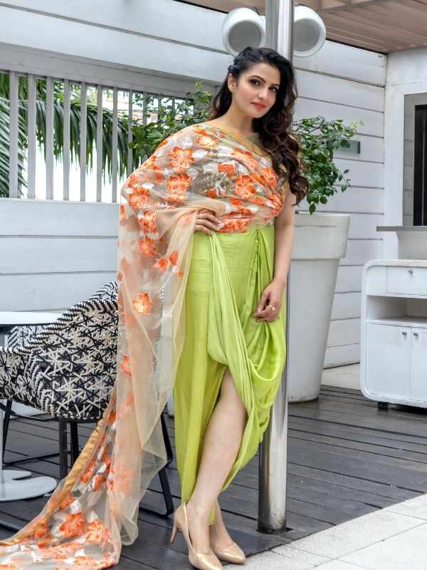 এক দিন শুধু শাড়ি। তবে এ শাড়ি বন্ধনমুক্ত। এতটাই অভিনব যে, এক নজরে মনে হতেই পারে ড্রেস। শাড়ির সঙ্গেই গাঁথা ব্লাউজ। তাতে এমব্রয়ডারির সূক্ষ্ম কাজ। সাদা নেটের আঁচলে কমলা ফুলের কারুকাজ যেন শরীর ছুঁয়ে সীমানা পেরোতে চায়!