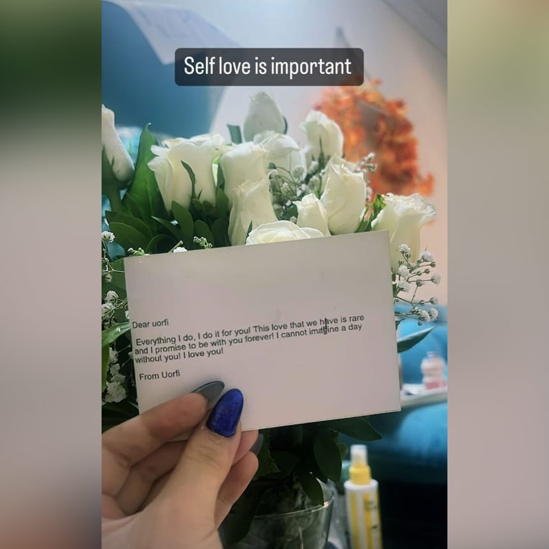 একগুচ্ছ সাদা গোলাপ কাচের ফুলদানিতে, তার সামনে চিরকুট মেলে ধরেছেন উরফি।