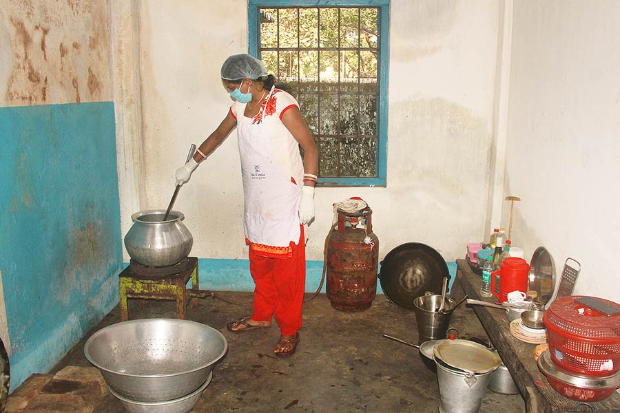 A photograph of a woman cooking in the mid day meal kitchen of a school 